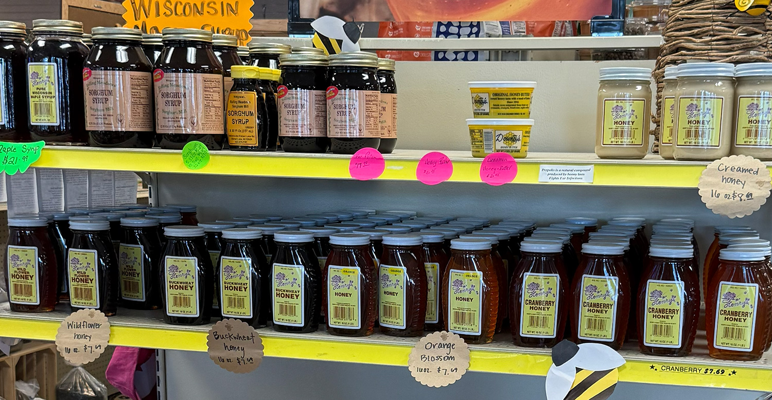 Shelves with jars of natural and flavored honey, sorghum syrup